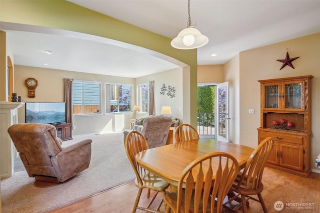 dining space featuring recessed lighting, arched walkways, and light wood finished floors