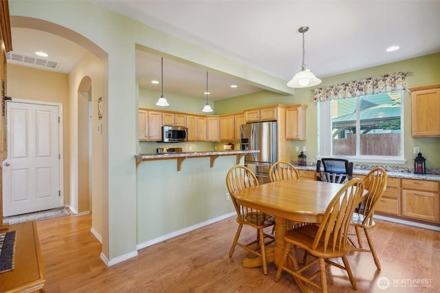 dining space featuring arched walkways, baseboards, light wood finished floors, and visible vents
