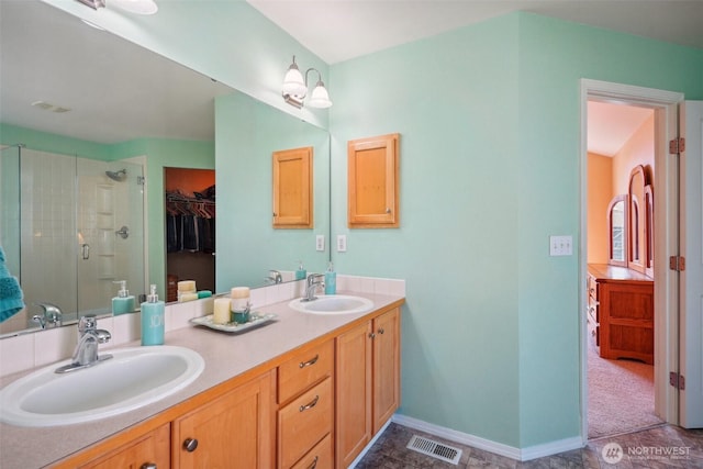 bathroom with a sink, a shower stall, double vanity, and visible vents