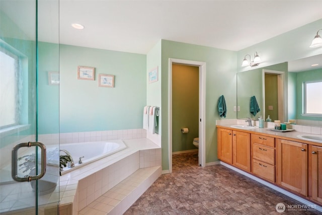 bathroom featuring double vanity, a sink, a bath, and toilet