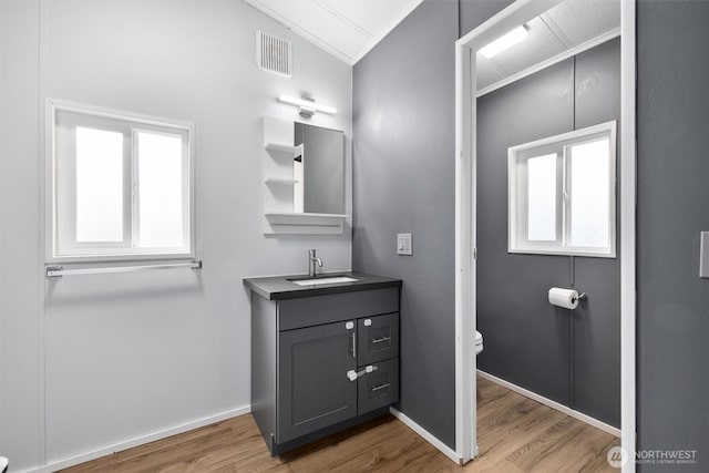 bathroom with vanity, toilet, wood finished floors, lofted ceiling, and visible vents