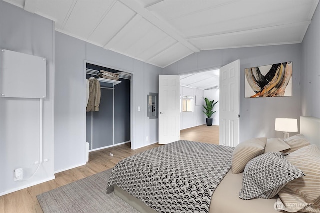 bedroom with a closet, baseboards, vaulted ceiling with beams, wood finished floors, and electric panel
