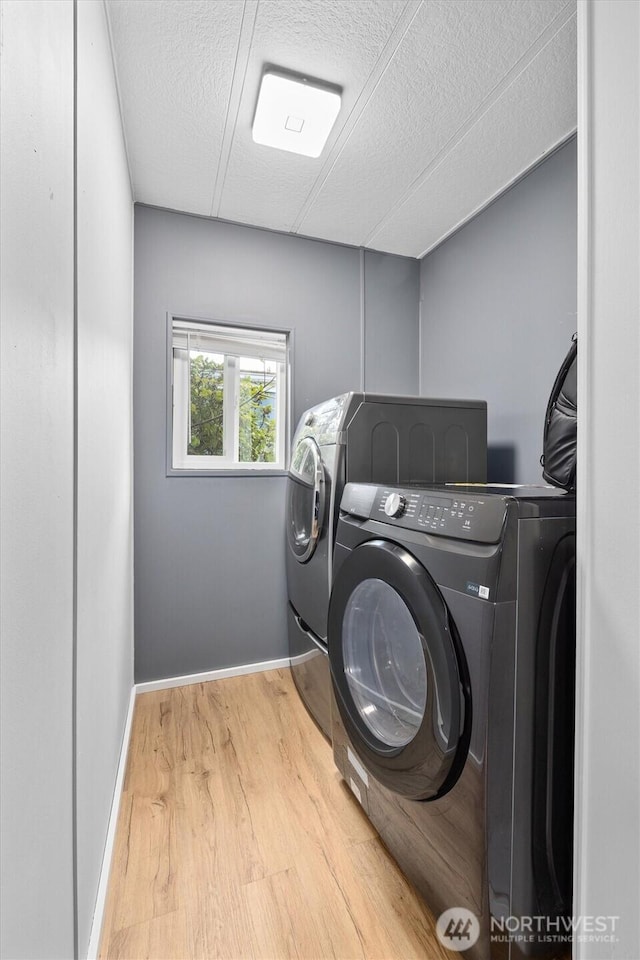 washroom with laundry area, separate washer and dryer, a textured ceiling, baseboards, and wood finished floors