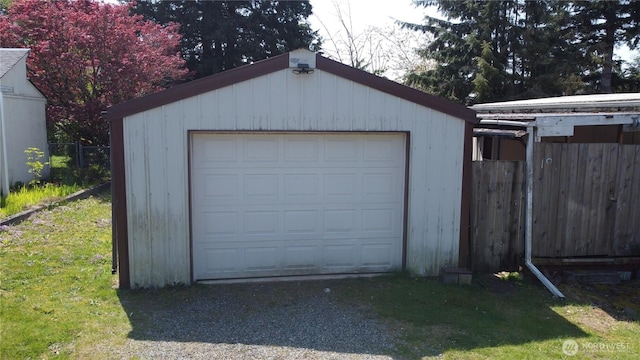 detached garage featuring fence and driveway