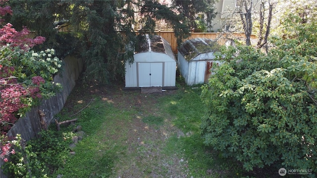 view of yard with a storage shed, fence, and an outbuilding