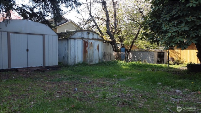 view of yard with a storage shed, fence, and an outbuilding