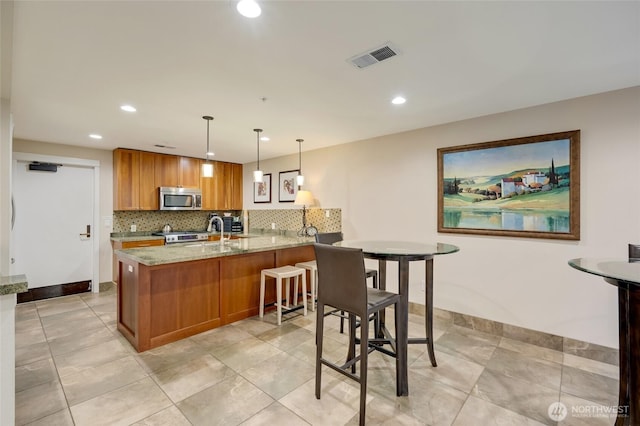 109 2nd St S Unit 523, Kirkland, WA 98033 - kitchen with brown cabinetry, appliances with stainless steel finishes, tasteful backsplash, light stone counters, and recessed lighting