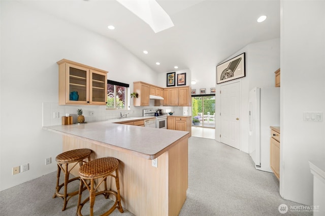 351 19th St NE Unit 10, East Wenatchee, WA 98802 - kitchen with light brown cabinets, white appliances, a peninsula, under cabinet range hood, and a skylight