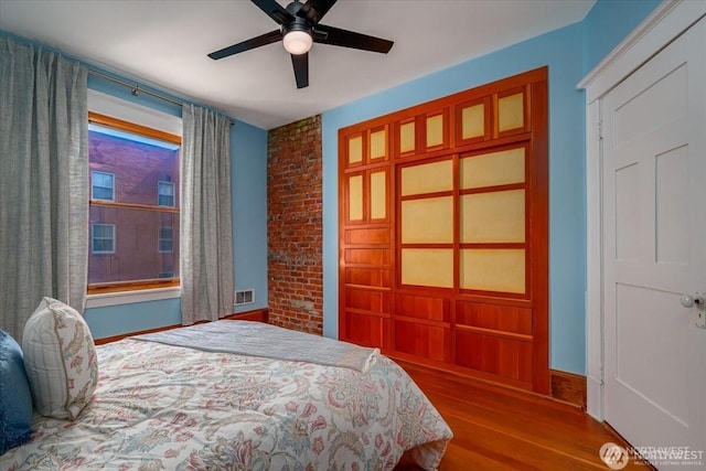 bedroom with visible vents, a ceiling fan, baseboards, and wood finished floors