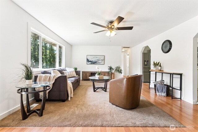 living room with arched walkways, ceiling fan, and wood finished floors