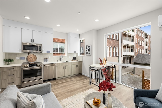1124C 13th Ave, Seattle, WA 98122 - kitchen featuring stainless steel appliances, a sink, light wood-style floors, backsplash, and light countertops