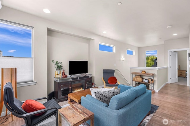 living room featuring baseboards, recessed lighting, and light wood-style flooring