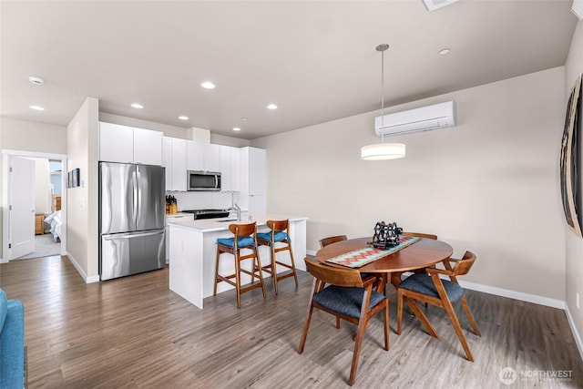 dining area featuring baseboards, a wall unit AC, and wood finished floors
