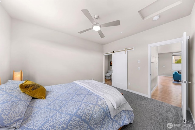 bedroom with ceiling fan, a barn door, carpet floors, attic access, and baseboards