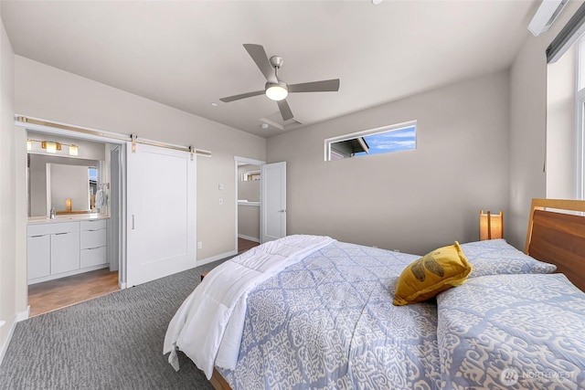 bedroom with ceiling fan, a barn door, a sink, baseboards, and connected bathroom