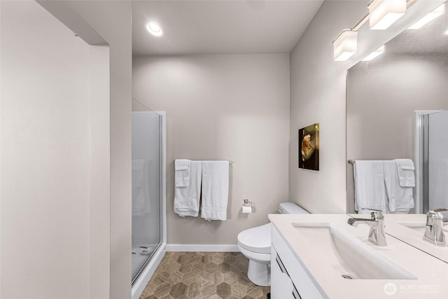 bathroom featuring toilet, baseboards, a shower stall, and vanity