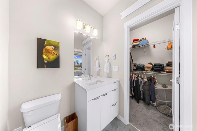 bathroom with vanity, toilet, and a spacious closet