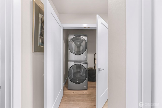 washroom featuring laundry area, stacked washer and clothes dryer, and wood finished floors