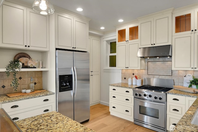 3122 SW 172nd St, Burien, WA 98166 - kitchen featuring appliances with stainless steel finishes, under cabinet range hood, light wood-type flooring, light stone counters, and decorative backsplash