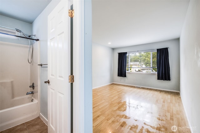 full bath featuring baseboards, wood finished floors, and  shower combination