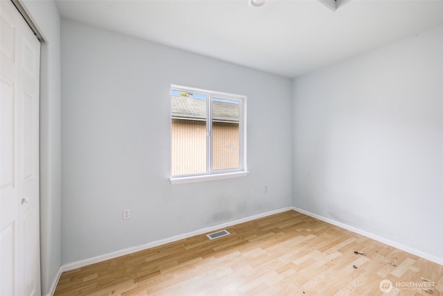 spare room with baseboards, visible vents, and wood finished floors