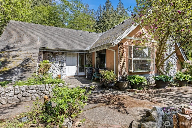 ranch-style house with roof with shingles and stone siding