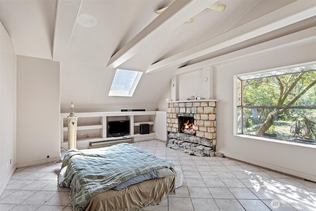 bedroom featuring baseboards, light tile patterned floors, vaulted ceiling with skylight, and a fireplace