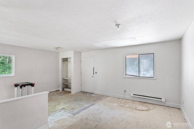 unfurnished room featuring concrete flooring, a textured ceiling, baseboards, and a baseboard radiator