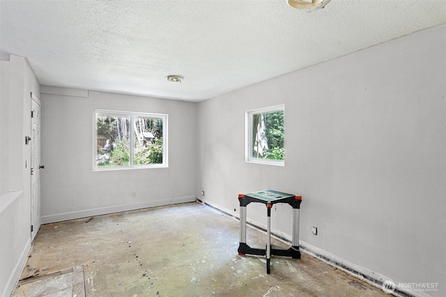 unfurnished bedroom with baseboards, a textured ceiling, concrete flooring, and multiple windows