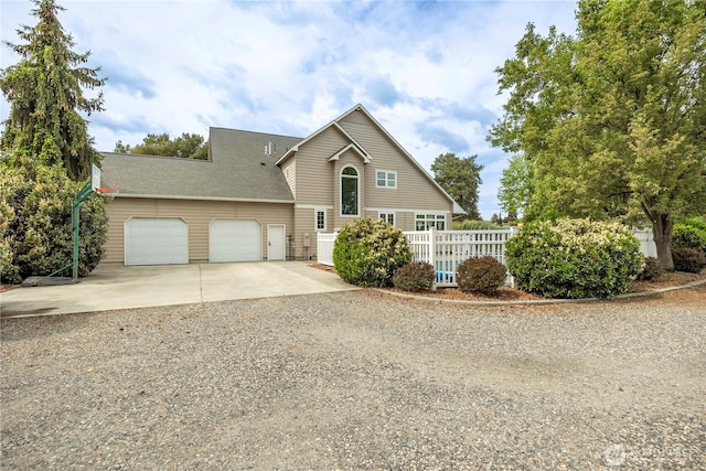view of front of house with fence, an attached garage, and driveway