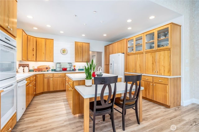 kitchen with a kitchen island with sink, light wood-style floors, white refrigerator with ice dispenser, recessed lighting, and light countertops