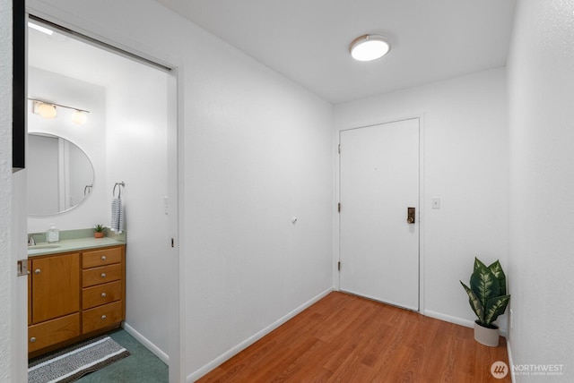 corridor with baseboards and light wood-type flooring