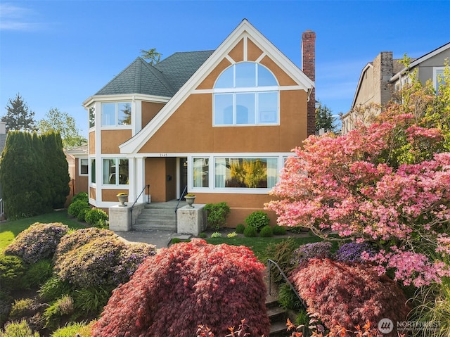 tudor-style house with a chimney and stucco siding