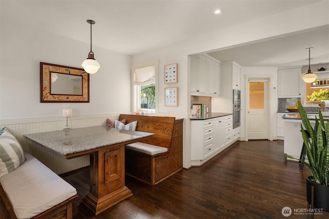 dining space with dark wood-style flooring, recessed lighting, breakfast area, and a wainscoted wall