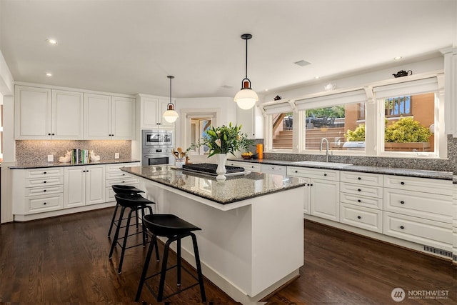 kitchen featuring a kitchen island, stainless steel appliances, a sink, and tasteful backsplash