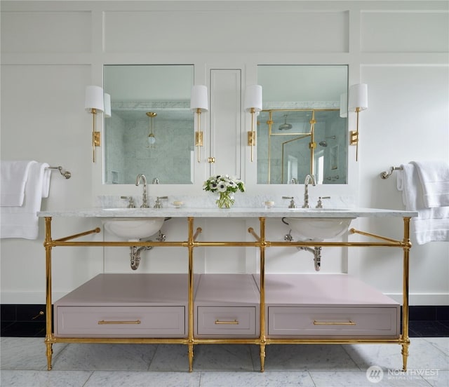 full bathroom with baseboards, double vanity, a sink, and a shower with shower door