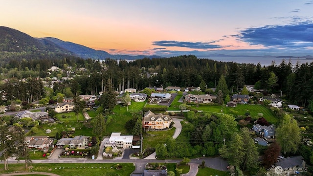 aerial view at dusk featuring a forest view, a residential view, and a mountain view