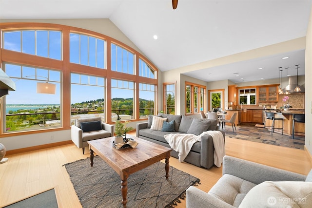 living area with recessed lighting, light wood finished floors, and high vaulted ceiling