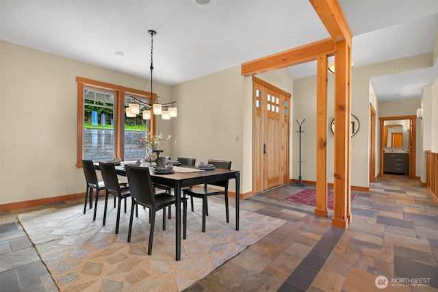dining room with baseboards, a notable chandelier, and stone tile flooring