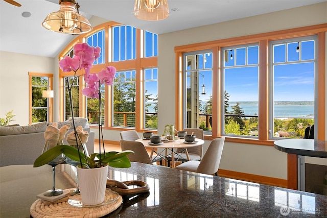 dining area with a water view, baseboards, vaulted ceiling, and wine cooler
