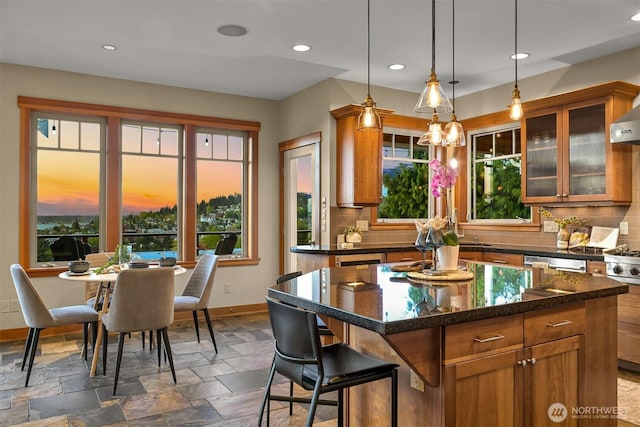 kitchen with stone tile floors, decorative backsplash, brown cabinets, and a healthy amount of sunlight