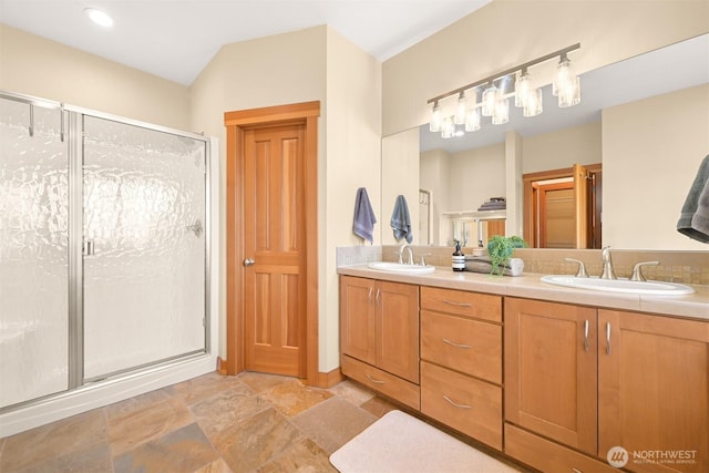 bathroom featuring double vanity, stone finish floor, a sink, and a stall shower