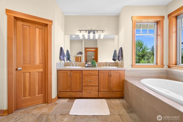 full bathroom featuring double vanity, stone finish floor, a sink, and a garden tub