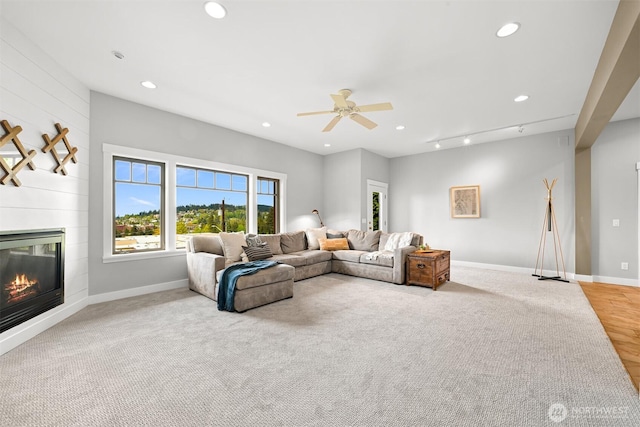 carpeted living area with recessed lighting, ceiling fan, baseboards, and a fireplace