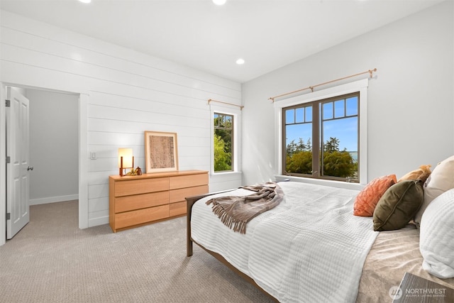 bedroom with recessed lighting, wood walls, baseboards, and light carpet