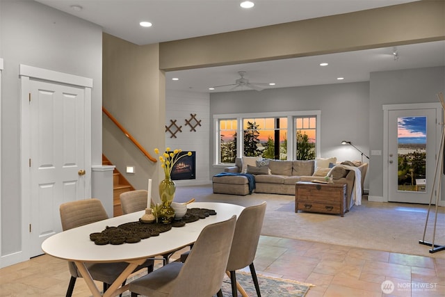 dining space with ceiling fan, a fireplace, recessed lighting, and stairs