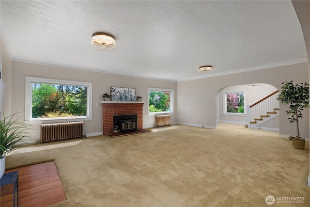 437 NW Pennsylvania Ave, Chehalis, WA 98532 - unfurnished living room with carpet flooring, arched walkways, radiator, ornamental molding, and stairway