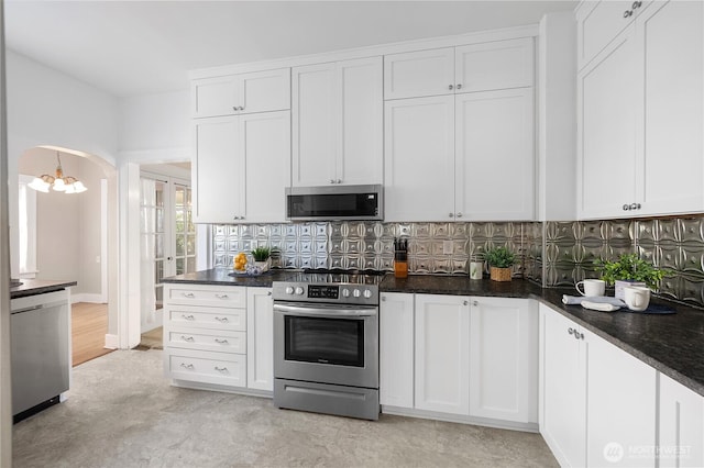 437 NW Pennsylvania Ave, Chehalis, WA 98532 - kitchen with arched walkways, appliances with stainless steel finishes, white cabinetry, and tasteful backsplash