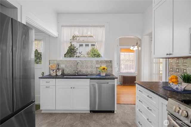 437 NW Pennsylvania Ave, Chehalis, WA 98532 - kitchen featuring appliances with stainless steel finishes, tasteful backsplash, dark countertops, radiator heating unit, and white cabinetry