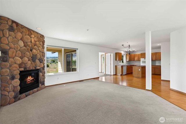 300 Range View Rd, Ellensburg, WA 98926 - unfurnished living room with a chandelier, light colored carpet, a stone fireplace, baseboards, and recessed lighting